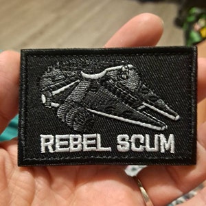 May include: Black embroidered patch with a white spaceship and the text "Rebel Scum".