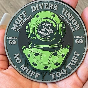 May include: A green and gray patch with a diving helmet and the text "Muff Divers Union of the Clam Local 69 No Muff Too Tuff".