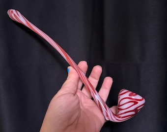 May include: A hand-blown glass pipe with a red and white swirl pattern. The pipe has a curved stem and a rounded bowl. The colours are vibrant, and the design is striking, making it a unique piece of art.