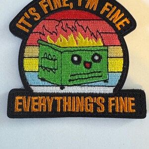 May include: Embroidered patch with the phrase "IT'S FINE, I'M FINE" arched above a cartoon dumpster on fire. The dumpster has a face and is set against a sunset background. The text "EVERYTHING'S FINE" is below.