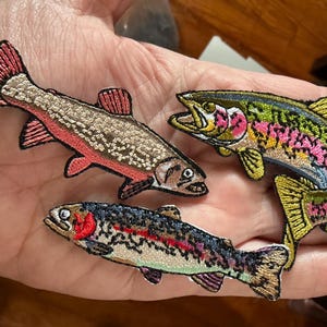 May include: Embroidered fish patches in various colors, including pink, green, and brown. The patches depict different species of fish, with detailed stitching and vibrant hues. Ideal for adding to clothing or accessories.