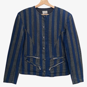 May include: A blue and gray striped jacket with a round collar and four buttons down the front. The jacket has two zippered pockets and is hanging on a wooden hanger.