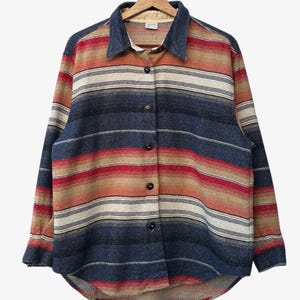May include: A striped button-down shirt in blue, red, beige and cream. The shirt has a denim collar and long sleeves. The shirt is displayed on a wooden hanger. The shirt's measurements are in centimetres.