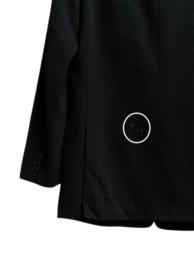 K&ouml;nnte beinhalten: Ein schwarzer Blazer mit fallendem Revers und drei Kn&ouml;pfen am &Auml;rmel. Der Blazer hat ein klassisches Design und ist aus einem einfarbigen, dunklen Stoff gefertigt. Das Bild zeigt eine Nahaufnahme der R&uuml;ckseite des Blazers.