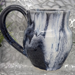 May include: A set of three ceramic mugs with a speckled, matte finish. The mugs are in shades of cream, light gray, and dark gray. Each mug has a simple, minimalist design, perfect for coffee or tea.