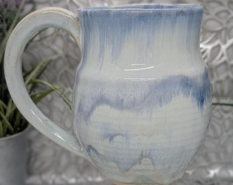 Hand thrown lightly ribbed 26 oz tall porcelain mug in light creamy green with blue streaks.