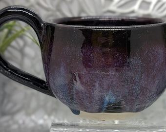 Hand thrown 16 oz short footed porcelain traditional coffee cup in obsidian purple maroon blue and gold glaze combination.