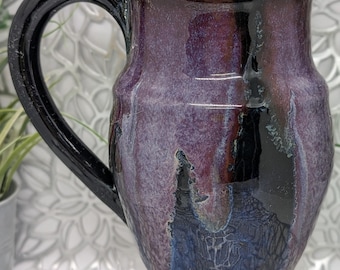 Hand thrown 22 oz tall porcelain mug in obsidian purple maroon blue and gold glaze.