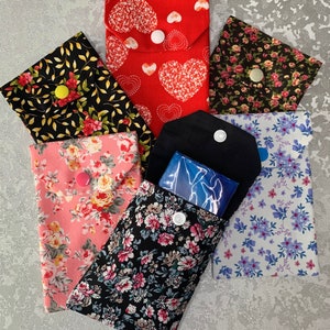 May include: Six fabric pouches with different floral patterns and a single snap closure. The pouches are arranged in a semi-circle with a blue pouch in the centre.