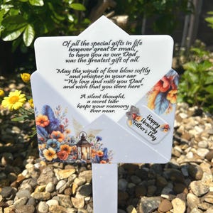 May include: A white memorial garden stake shaped like an envelope, featuring floral designs in orange, blue, and yellow. The stake has the text "Happy Heavenly Father's Day" and a poem about a father.