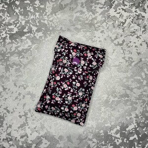 May include: A small purple fabric pouch with a floral print. The pouch has a flap with a purple button closure.