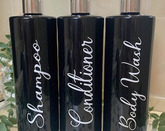 May include: Three black pump bottles with silver tops and white labels. The labels read "Shampoo", "Conditioner", and "Body Wash".