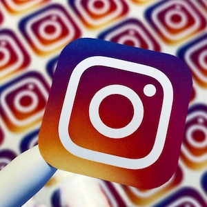 Pu&ograve; includere: Un primo piano di un adesivo con il logo di Instagram. Il logo &egrave; un'icona di una fotocamera bianca con un cerchio bianco all'interno, su uno sfondo sfumato di rosso, arancione, giallo e blu. L'adesivo &egrave; circondato da altri adesivi con il logo di Instagram.