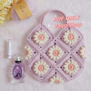 Puede incluir: Una bolsa de crochet con un patrón de margaritas rosa y blancas. La bolsa tiene un solo asa y está hecha con un hilo de color morado claro. El texto "PDF ONLY ZaqqiShop" es visible en la bolsa.