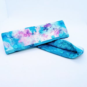 May include: A pair of blue and pink tie dye fabric wrist cuffs with turquoise snap buttons.
