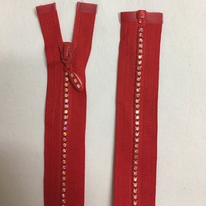 May include: Two red zippers with a line of clear iridescent rhinestones down the center of each zipper.