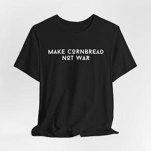 May include: Black t-shirt with white text that reads "MAKE CORNBREAD NOT WAR"