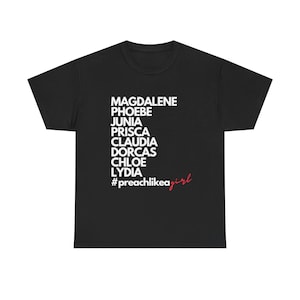 May include: Black t-shirt with white text listing names: Magdalene, Phoebe, Junia, Prisca, Claudia, Dorcas, Chloe, Lydia. Below the names is the hashtag #preachlikeagirl in white and red script.