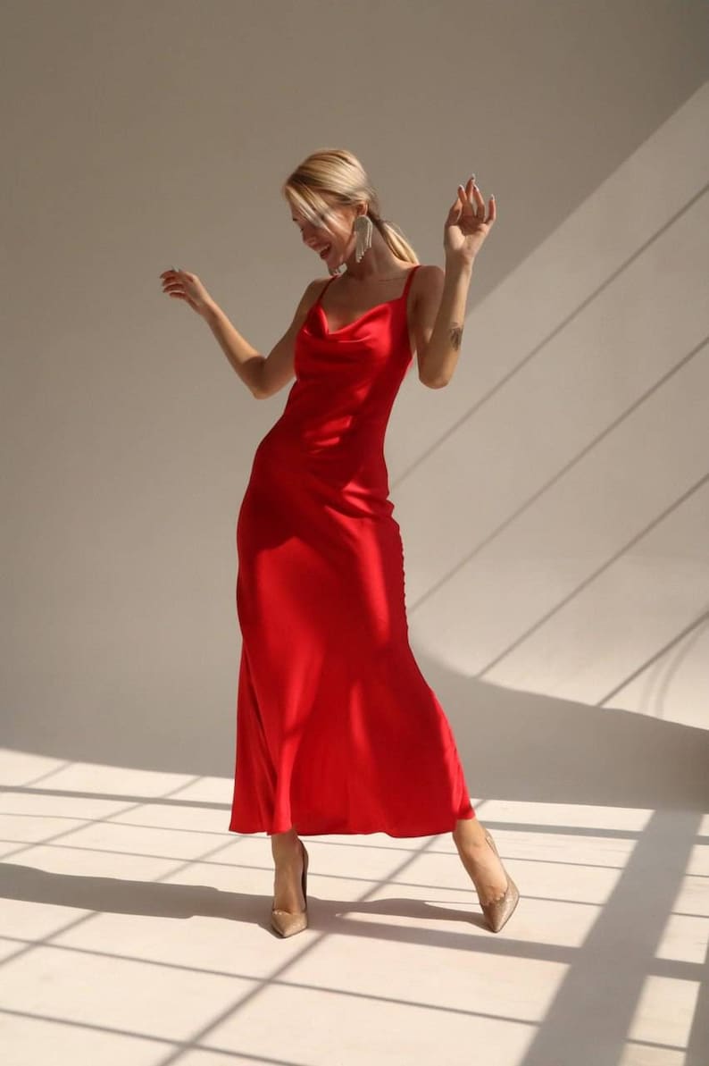 A red satin midi dress with a cowl neck and spaghetti straps.