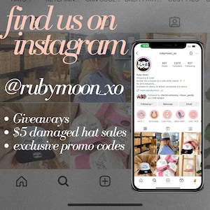 Op de afbeelding: Het scherm van een mobiele telefoon toont een social media pagina voor een bedrijf genaamd Ruby Moon. De pagina heeft een logo met een rode maan en de tekst "Ruby Moon". De pagina bevat ook informatie over het bedrijf, zoals de locatie, contactgegevens en een link naar de website. De pagina bevat ook een call-to-action om het bedrijf te volgen op Instagram. De tekst "find us on instagram @rubymoon_xo" wordt boven het telefoonscherm weergegeven. Onder het telefoonscherm wordt de tekst "Giveaways, &euro;5 beschadigde hoedverkoop, exclusieve promocodes" weergegeven.