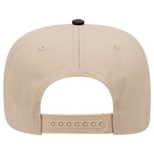 Op de afbeelding: Een beige en zwarte baseballpet met een zwarte verstelbare band en het woord "OTTO" gedrukt op de band.