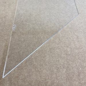 May include: A clear plastic triangle ruler with the word "FOLD" printed on the left side and "X-Large" printed on the top.