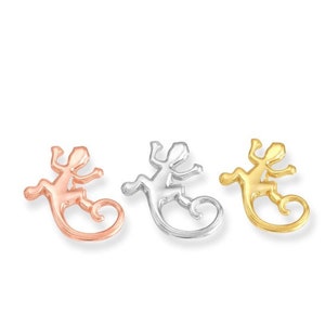 May include: Three lizard charms in different metal finishes: rose gold, silver, and gold. Each charm features a detailed lizard design with a curled tail.