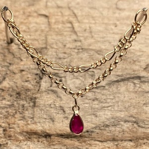 May include: A gold chain necklace with a teardrop-shaped ruby pendant.