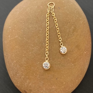 14 karat solid gold double bezel Dangle attachment. 5/8 inch and 3/4 inch drop downs Fits any 14 ,16, 18 gauge Piercing Two 2.5mm CZ