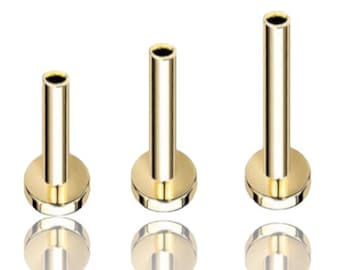 May include: Three gold-colored surgical steel body jewelry pieces, each with a flat base and a cylindrical post. The pieces are arranged in order of size, with the smallest on the left and the largest on the right.