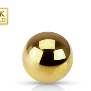May include: A shiny, golden sphere with a reflective surface. The image includes a small square label that reads "14K GOLD". The sphere is a solid, round shape, and the background is white.