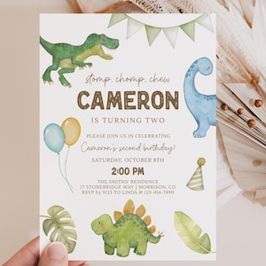May include: A birthday invitation with a dinosaur theme. The invitation features illustrations of green and blue dinosaurs, balloons, and a party hat. The text reads "Cameron is turning two" and includes party details.