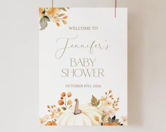 May include: A white rectangular sign featuring the text WELCOME TO Jennifer's BABY SHOWER OCTOBER 8TH, 2026. The design includes watercolor illustrations of orange and yellow autumn leaves, berries, and a large white pumpkin at the base.