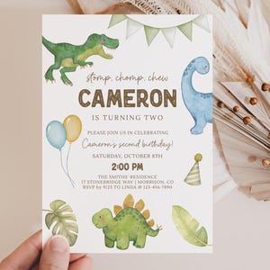 May include: A birthday invitation featuring watercolor illustrations of dinosaurs, balloons, and foliage. The text reads "Cameron is turning two" with event details. The invitation is held by a hand.