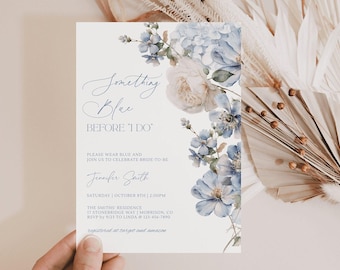 May include: A white rectangular invitation card featuring blue and cream watercolor floral illustrations on the right side. The text reads: Something Blue BEFORE I DO, PLEASE WEAR BLUE AND JOIN US TO CELEBRATE BRIDE-TO-BE, Jennifer Smith, SATURDAY | OCTOBER 8TH | 2:00PM, THE SMITHS' RESIDENCE, 17 STONEBRIDGE WAY | MORRISON, CO, RSVP by 9/23 TO LINDA @ 123-456-7890, registered at target and amazon.
