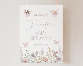 May include: A white rectangular sign featuring the text WELCOME TO Jennifer's BABY SHOWER JUNE 17TH, 2026. The design includes two watercolor fairies, two butterflies, and a bottom border of colorful wildflowers in pink, purple, and green.