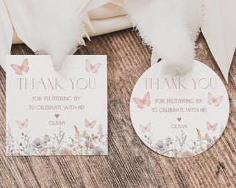May include: A square and a circular white paper gift tag, each featuring pink butterflies, a floral border, and the text THANK YOU FOR FLUTTERING BY TO CELEBRATE WITH ME! with the name OLIVIA and a small heart icon printed in pink ink.