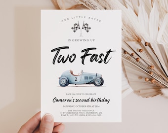 Op de afbeelding: Een witte rechthoekige verjaardagsuitnodigingskaart met de tekst Our Little Racer Is Growing Up, Two Fast en Race On Over To Celebrate Cameron's Second Birthday. Het bevat een lichtblauwe vintage raceauto met het nummer 2.