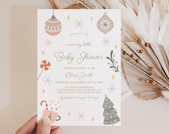 May include: A baby shower invitation with a festive winter theme. The invitation features decorative ornaments, snowflakes, and a Christmas tree. The text reads "Join us for a merry little Baby Shower" and includes the honoree's name, date, and location.
