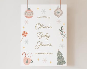May include: A baby shower welcome sign with a festive design. The sign features a light background with decorative elements like baubles, snowflakes, and a Christmas tree. The text reads "Welcome to Olivia's Baby Shower" and the date.
