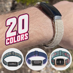 Puede incluir: Un rastreador de actividad física negro con una correa beige tejida se lleva en la muñeca. La imagen muestra tres correas adicionales con diferentes patrones y colores. El texto "20 COLORS" se muestra en rosa y blanco.