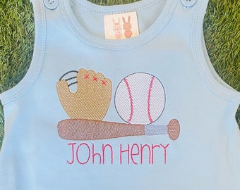May include: Light blue sleeveless baby onesie with a baseball, bat, and glove embroidered on the front. The onesie has the name "John Henry" embroidered below the baseball equipment.