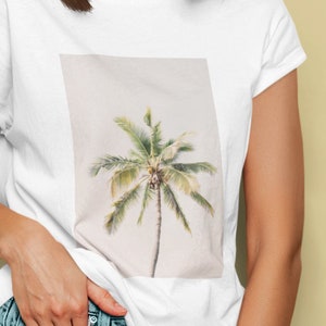 May include: White t-shirt with a palm tree graphic. The shirt is paired with denim shorts. The image shows a person wearing the shirt and shorts, with yellow-tinted glasses.