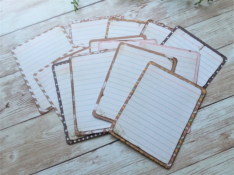 May include: A set of lined paper cards with decorative borders in brown, black, and pink. The cards are perfect for journaling, scrapbooking, or crafting.