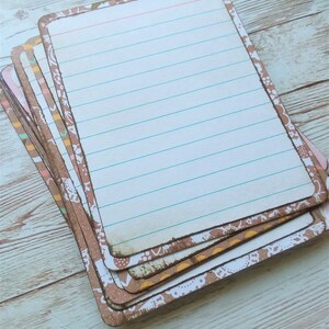 May include: A stack of blank note cards with a brown and white patterned border. The cards have lined paper and are perfect for writing notes, lists, or reminders.