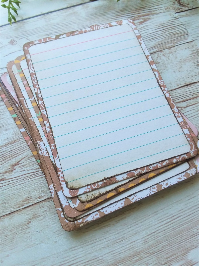 May include: A stack of blank note cards with a brown and white patterned border. The cards have lined paper and are perfect for writing notes, lists, or reminders.