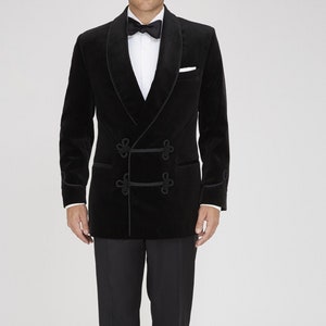 May include: A formal black velvet double-breasted tuxedo jacket with black trousers, a white dress shirt, and a black bow tie. The jacket has a shawl collar and decorative buttons. The outfit is completed with black dress shoes.