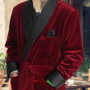May include: A long, red velvet robe with a black quilted collar and matching cuffs. The robe has a sash tie and two pockets.