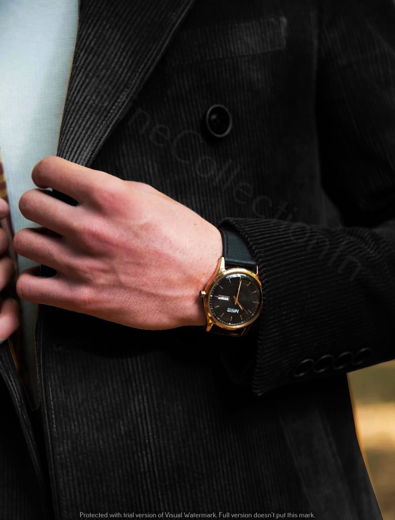 May include: A gold-toned wristwatch with a black leather band and a black face. The watch has a date window and a small second hand.