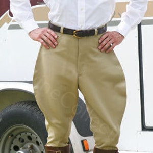 May include: Beige riding breeches with a brown leather belt. The breeches have a slightly flared leg and are made of a smooth, lightweight fabric.
